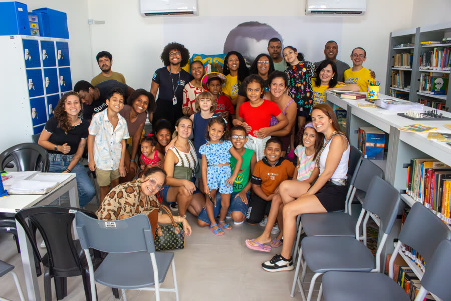 Famílias e crianças participantes da Oficina de Contação de Histórias reunidas na biblioteca ao final da atividade