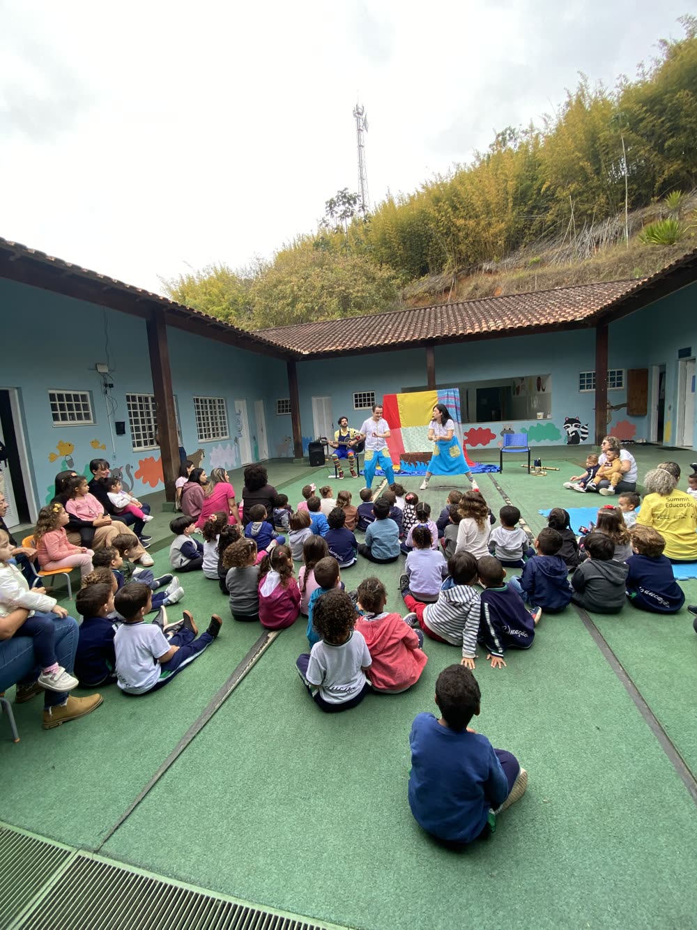 Apresentação da Valiante no pátio de uma escola, com crianças sentadas em roda assistindo